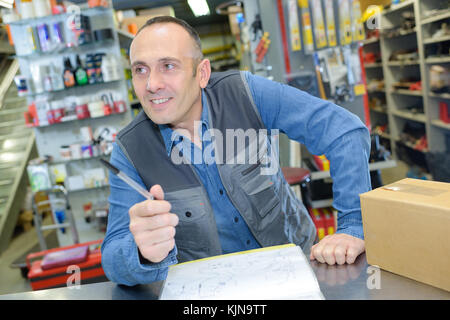 Smiling man caisse debout à payer 24 dans le ménage store Banque D'Images