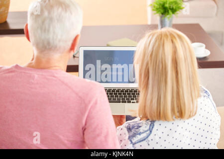 Vue arrière Vue d'un senior couple using a laptop alors que la banque en ligne à la maison. Banque D'Images