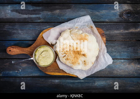 Moyen orient traditionnel apéritif houmous servi avec pain pita frais. sur une planche de bois. Vue de dessus Banque D'Images