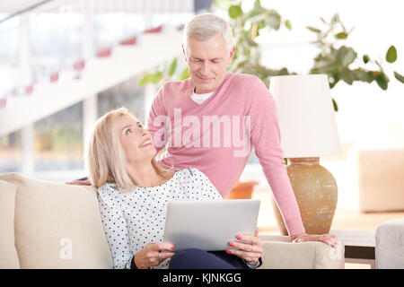 Tourné d'une belle vieille femme et senior man sitting on sofa and using laptop. Banque D'Images