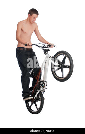 Teenage boy standing on les patères arrière d'un vélo BMX lors d'acrobaties. Banque D'Images