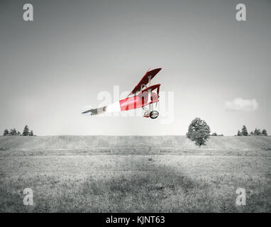 Vol de fantaisie d'un vieux rouge vol d'un avion sur un champ et le ciel en noir et blanc Banque D'Images