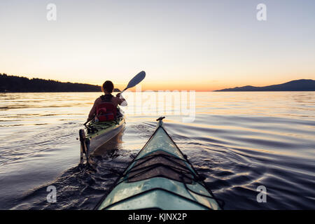 Kayak de mer dans l'océan lors d'un coucher de soleil colorés et dynamiques. prises à Jéricho, Vancouver, Colombie-Britannique, Canada. Banque D'Images