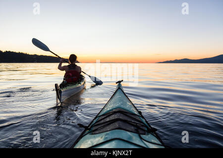 Kayak de mer dans l'océan lors d'un coucher de soleil colorés et dynamiques. prises à Jéricho, Vancouver, Colombie-Britannique, Canada. Banque D'Images