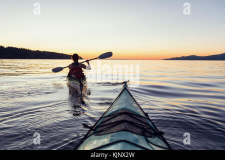 Kayak de mer dans l'océan lors d'un coucher de soleil colorés et dynamiques. prises à Jéricho, Vancouver, Colombie-Britannique, Canada. Banque D'Images