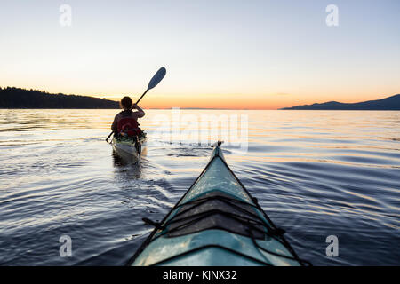 Kayak de mer dans l'océan lors d'un coucher de soleil colorés et dynamiques. prises à Jéricho, Vancouver, Colombie-Britannique, Canada. Banque D'Images