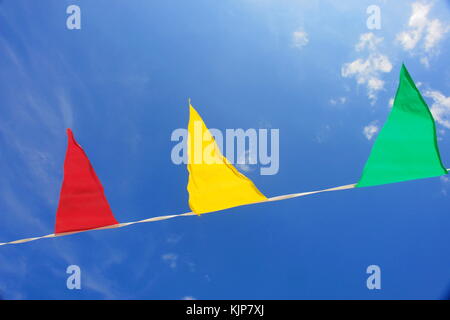 Drapeaux triangulaires multicolores suspendus dans le ciel à une piscine celebration party. Banque D'Images