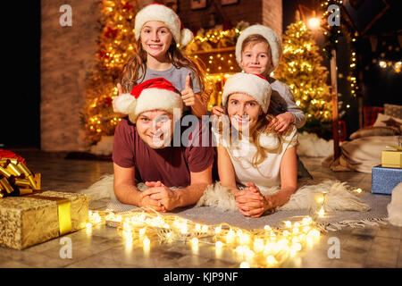 Famille dans une pièce avec un arbre de Noël le jour de Noël. Banque D'Images