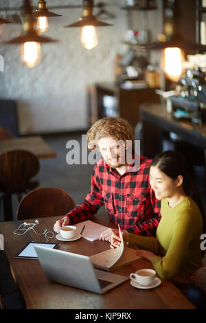 Deux étudiants moderne sittingin cafe après les cours et la lecture de l'information en ligne ou regarder la conférence en ligne Banque D'Images