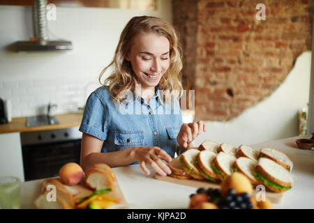 Femme blonde regardant un groupe de sandwichs savoureux faits par elle Banque D'Images