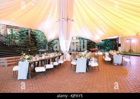 Vacances, congés, l'établissement concept. Il n'y a woderful immense tente blanche sous longtemps servi de tables pour célébration d'anniversaire entouré de sapins toujours verts Banque D'Images