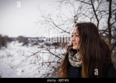 Pensive et fille romantique avec de beaux cheveux longs sur l'arrière-plan d'hiver à l'écart sur le paysage d'hiver Banque D'Images