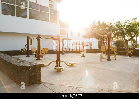 Une aire de jeux publique dans une petite ville d'Espagne avec des appareils de fitness de plein air au coucher du soleil Banque D'Images