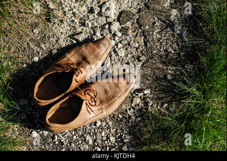 Vieilles chaussures d'hommes sur la piste dans l'herbe. Banque D'Images