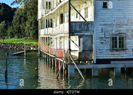 Bâtiment en bois vieilli de plusieurs étages du Bayswater Yacht Club debout sur des poteaux près de la rive dans les eaux peu profondes du port de Waitemata à Auckland. Banque D'Images