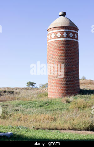 Photo d'un paysage ancien silo à grains en brique rouge dans un champ vert et jaune Banque D'Images