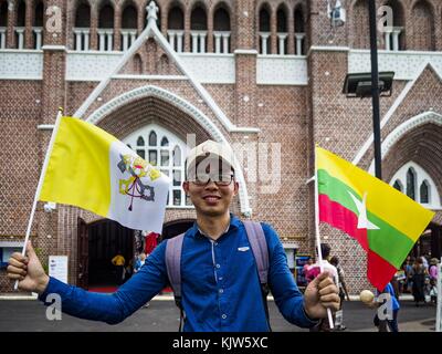 Yangon, région de Yangon, Myanmar. 26 novembre 2017. Un homme s'éloigne de la cathédrale de Marie après avoir acheté des drapeaux (drapeau du Vatican à gauche, drapeau du Myanmar à droite) honorant la visite du pape François au Myanmar. Le Pape visitera Yangon du 27 au 30 novembre. Il aura des entretiens privés avec des représentants du gouvernement, des chefs militaires et du clergé bouddhiste. Il participera également à deux messes, une messe publique dans un complexe sportif le 29 novembre et une messe pour les jeunes du Myanmar à la cathédrale Marie le 30 novembre. Crédit : Jack Kurtz/ZUMA Wire/Alamy Live News Banque D'Images