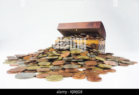 Un petit coffre au trésor en bois qui regorge de pièces sur un fond blanc. Composition isolée qui est liée à la situation économique et financière Banque D'Images