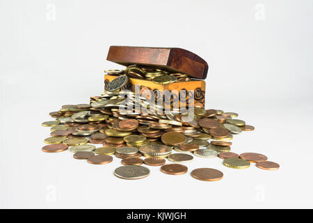 Un petit coffre au trésor en bois qui regorge de pièces sur un fond blanc. composition isolée qui est liée à la sphère économique Banque D'Images