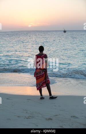 Zanzibar, Tanzanie ; les jeunes guerriers Massaïs sur la plage pour vendre bijoux Massaï et de l'artisanat traditionnel de leur cage à proximité pour les touristes à la plage hôtels dans le nord de l'île. Banque D'Images
