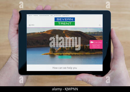 Un homme se penche sur la Severn Trent Water site sur son iPad tablet device, tourné contre une table en bois page contexte (usage éditorial uniquement) Banque D'Images