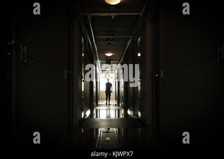 Homme marchant dans un long couloir sombre