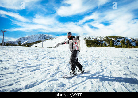 Jeune homme snowboard manèges et profiter d'une journée d'hiver ensoleillée sur les pentes des montagnes. Banque D'Images