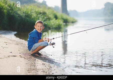 Happy boy avec la tige sur la côte de la rivière Banque D'Images