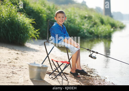 Happy boy avec la tige sur la côte de la rivière Banque D'Images