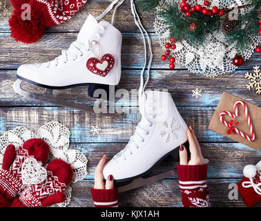 Girl in red sweater holding white patins sur un tableau bleu des vacances d'hiver Banque D'Images