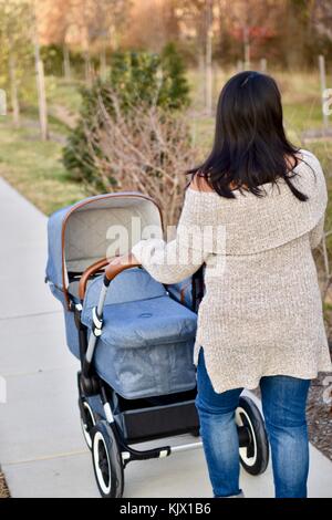 Femme poussant Bugaboo poussette sur le trottoir Banque D'Images