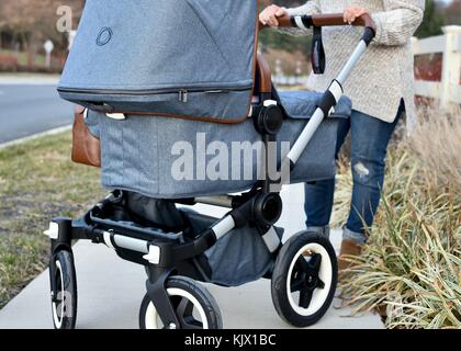 Femme poussant Bugaboo poussette sur le trottoir Banque D'Images