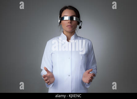 Female scientist ou votre médecin à l'aide de lunettes vr futuriste casque avec microphone et la tenue d'objet virtuel Banque D'Images