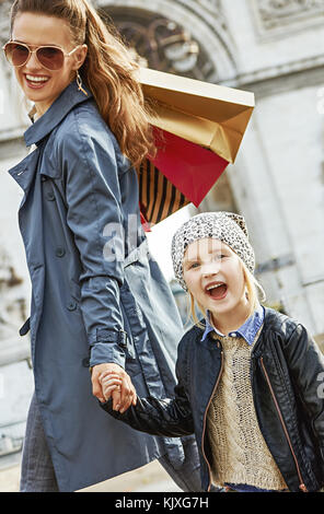 Automne élégant à paris. smiling trendy la mère et l'enfant avec les sacs près de l'arc de triomphe à Paris, France Banque D'Images