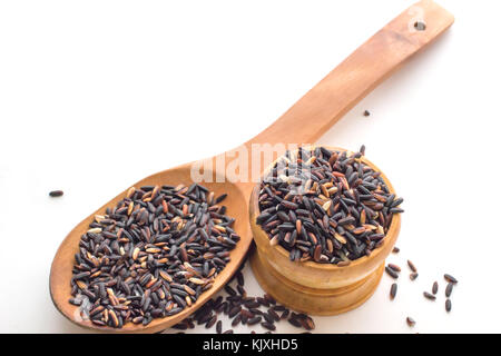 Berry de riz non cuit ou de riz brun dans un bol en bois sur fond blanc, noir ou de riz thaï au jasmin riz berry avec fond blanc. Banque D'Images