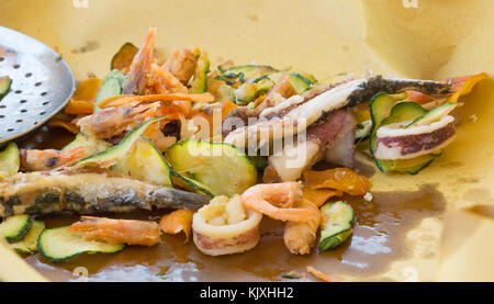 Poêlée de poisson et fruits de mer, légumes verts, poêlée de poisson avec les anchois, les calmars et les crevettes et légumes verts sur fond de papier brun. Banque D'Images