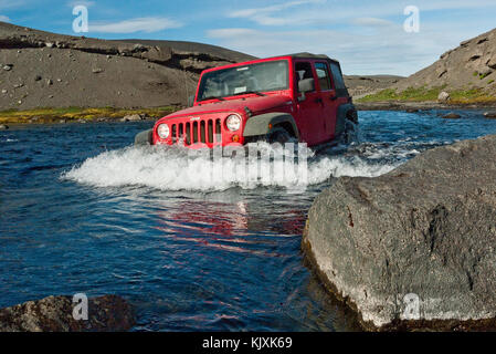 Une jeep rouge traverse un gué sur la route f910 en Islande Banque D'Images