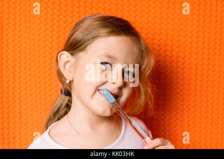 Petite fille avec une brosse à dents sur fond noir Banque D'Images