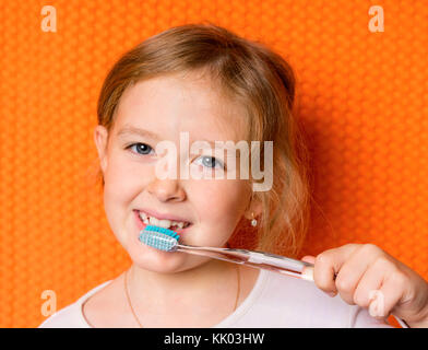 Petite fille avec une brosse à dents sur fond noir Banque D'Images