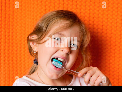 Petite fille avec une brosse à dents sur fond noir Banque D'Images