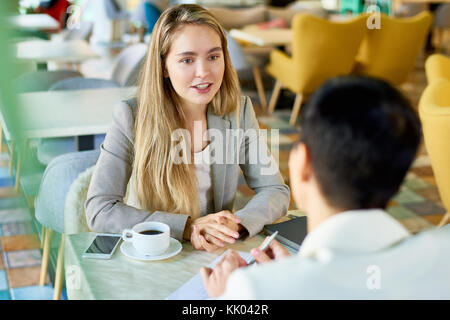 Portrait de deux jeunes femmes modernes discuter travailler assis à table dans un café pendant une réunion d'affaires ou d'entrevue d'emploi Banque D'Images