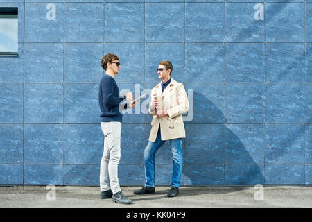 Portrait de deux jeunes hommes d'chat dehors au cours de pause café debout contre le mur de béton, copy space Banque D'Images