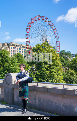 Edinburgh scotland Edinburgh Scottish piper jouant de la cornemuse devant les jardins de Princes street et du centre-ville d'édimbourg Royaume-Uni centre de roue Banque D'Images