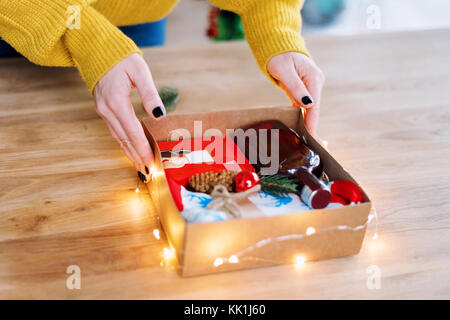 Emballage cadeau de Noël femme mains sur table en bois. Cadeaux à la maison Banque D'Images