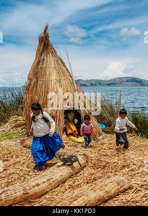 Les enfants autochtones uro jouant avec un chat, îles flottantes des Uros, lac Titicaca, région de Puno, Pérou Banque D'Images