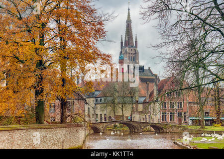 Vue d'automne du béguinage pont et église notre dame tower le long de la canal de Bruges avec des cygnes Banque D'Images