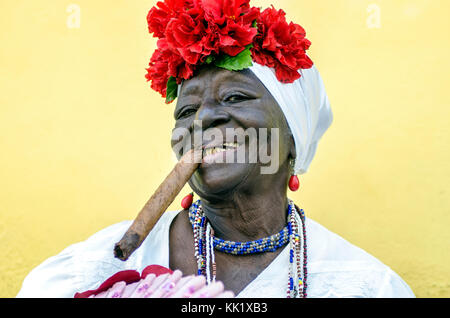 Une femme habillée excentriquement avec un cigare dans la bouche attend que les conseils soient photographiés par les touristes dans la vieille Havane, Cuba Banque D'Images