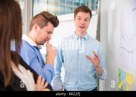 Businessman gesturing lors de la communication avec des collègues Banque D'Images