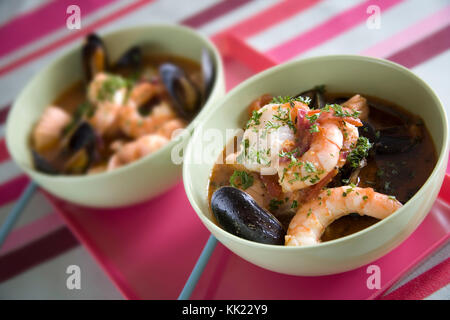 Soupe de crustacés avec les pétoncles, langoustines, moules et palourdes garni de persil frais haché Banque D'Images