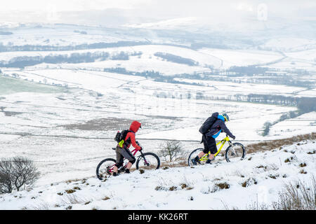 Deux cyclistes dans la neige en poussant les vélos, Rushup Edge, Derbyshire, Peak District, England, UK Banque D'Images